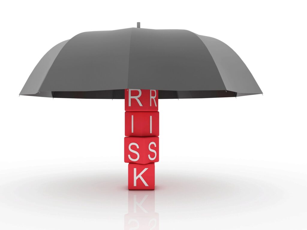 Composizione di cubi rossi con le lettere RISK coperti da un ombrello.