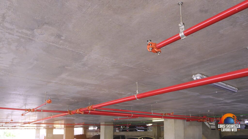 Impianto antincendio a soffitto con tubazioni rosse in autorimessa pubblica.